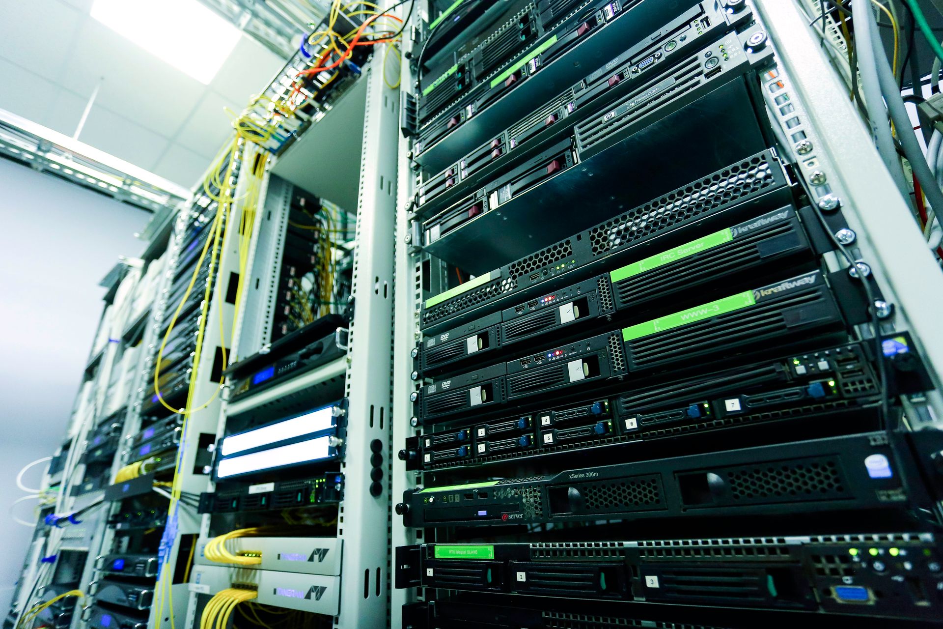 Server racks with rows of computer equipment and bundled network cables.