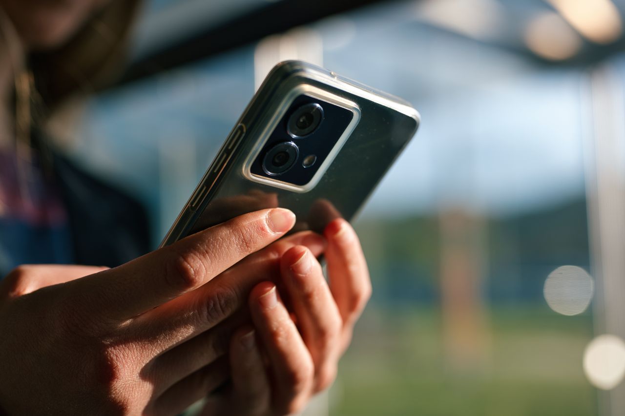 Hands holding a smartphone with the back of the phone facing the camera.