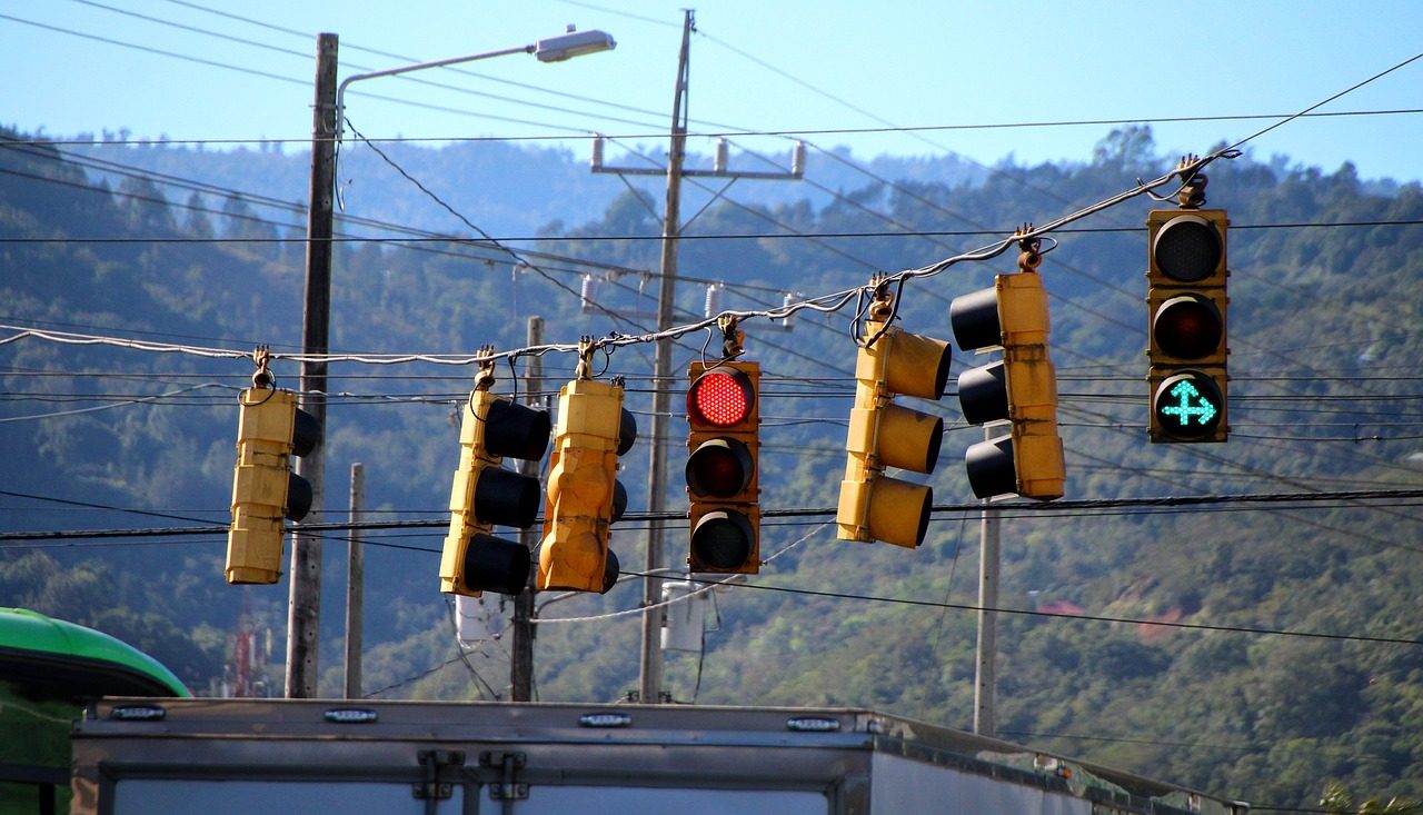 Yellow traffic lights hang from overhead wires above a road.